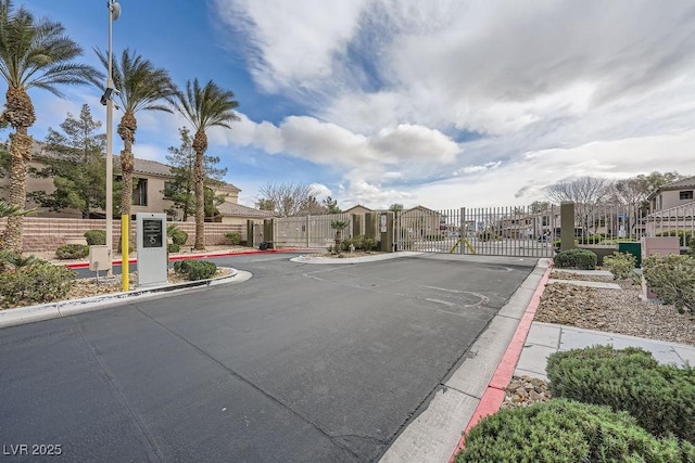 view of street with a residential view, a gate, a gated entry, and curbs