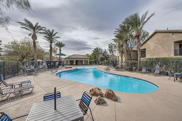 community pool with fence and a patio