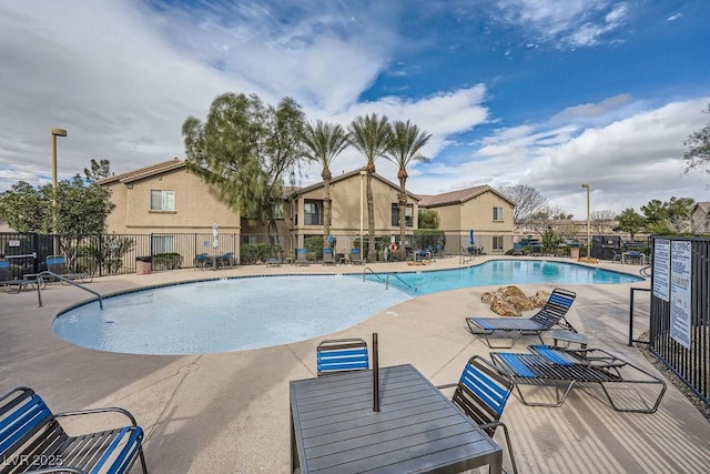 pool with a patio area and fence