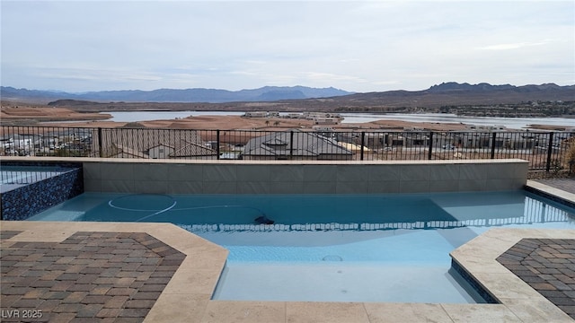 view of pool featuring a pool with connected hot tub, a patio area, fence, and a mountain view