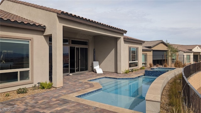 view of pool with a patio area, a pool with connected hot tub, and fence