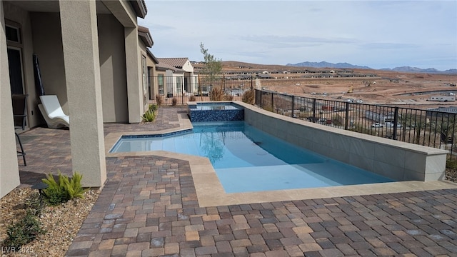 view of swimming pool featuring a pool with connected hot tub, a patio area, a fenced backyard, and a mountain view