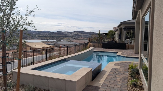 view of pool with a pool with connected hot tub, fence, and a mountain view