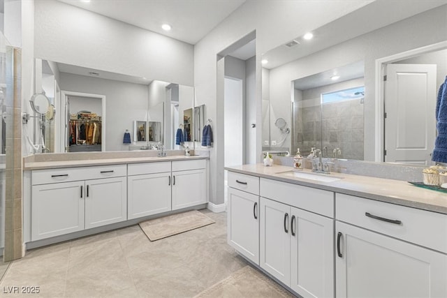 full bath featuring a stall shower, visible vents, a sink, a walk in closet, and two vanities