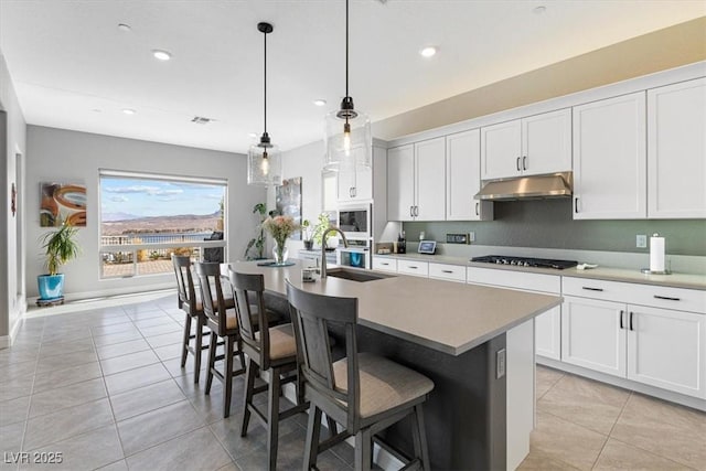 kitchen featuring a sink, under cabinet range hood, gas cooktop, and light tile patterned floors