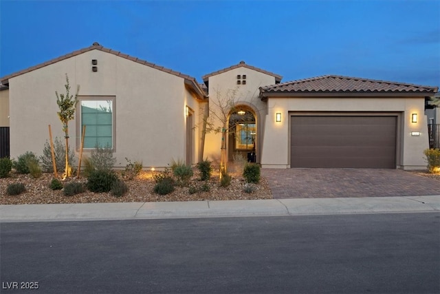 mediterranean / spanish home with driveway, an attached garage, a tile roof, and stucco siding