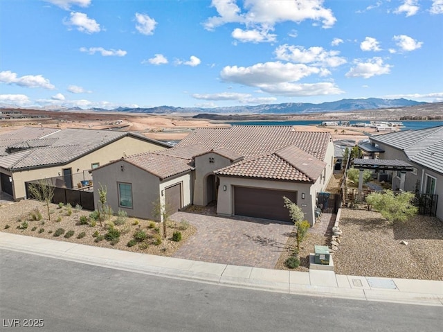 view of front of house with a garage, a tile roof, decorative driveway, a mountain view, and stucco siding