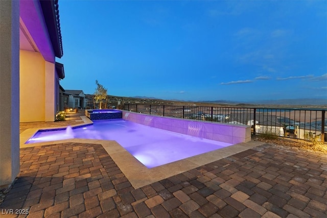 view of pool with a patio, fence, and a pool with connected hot tub