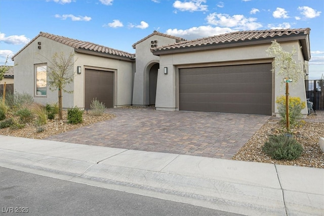 mediterranean / spanish-style house featuring a garage, decorative driveway, and stucco siding