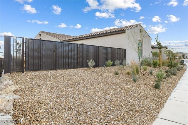 view of home's exterior with fence, a gate, and stucco siding