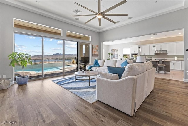 living room with recessed lighting, a raised ceiling, visible vents, a ceiling fan, and wood finished floors