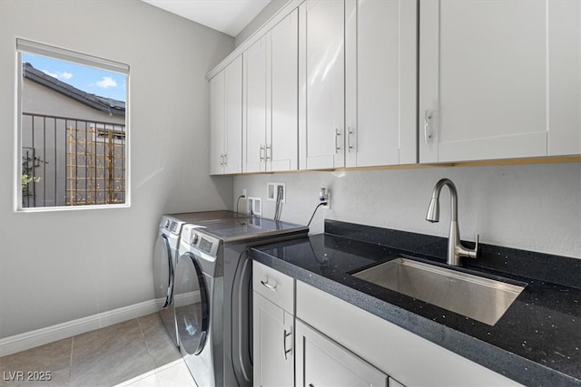 laundry area with washing machine and clothes dryer, cabinet space, light tile patterned flooring, a sink, and baseboards