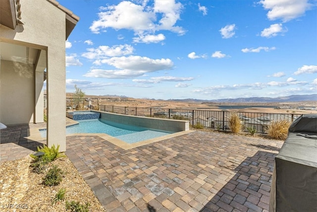 view of pool featuring a patio area, a fenced backyard, and a mountain view