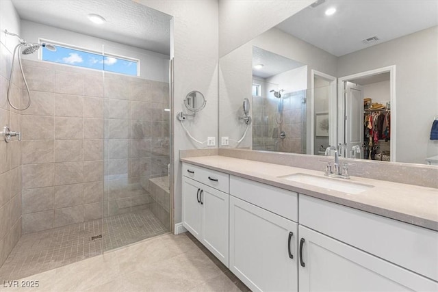 bathroom featuring visible vents, tile patterned floors, a walk in closet, vanity, and a shower stall