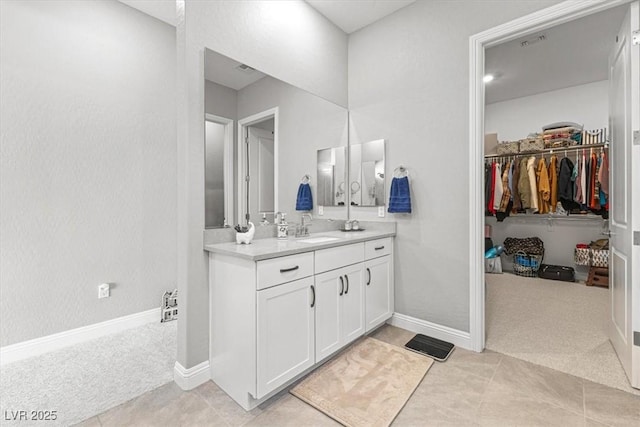 bathroom featuring tile patterned flooring, vanity, baseboards, and a spacious closet