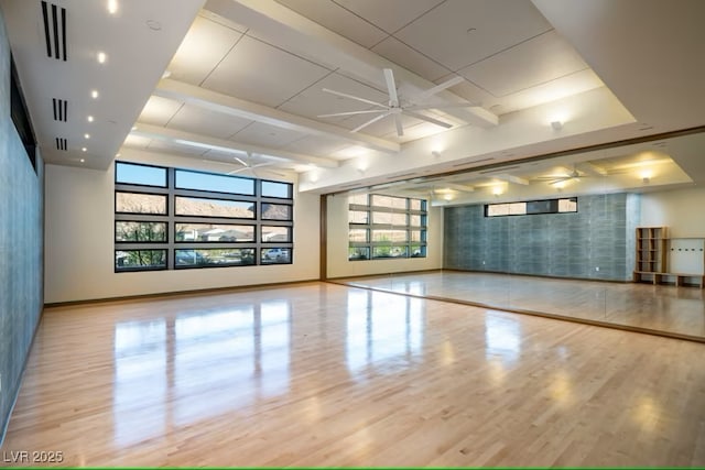 interior space featuring visible vents, a ceiling fan, wood finished floors, beamed ceiling, and baseboards