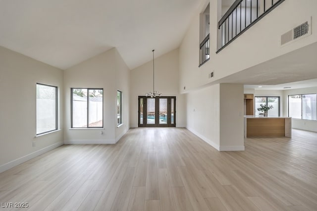 unfurnished living room featuring a healthy amount of sunlight, visible vents, and light wood finished floors