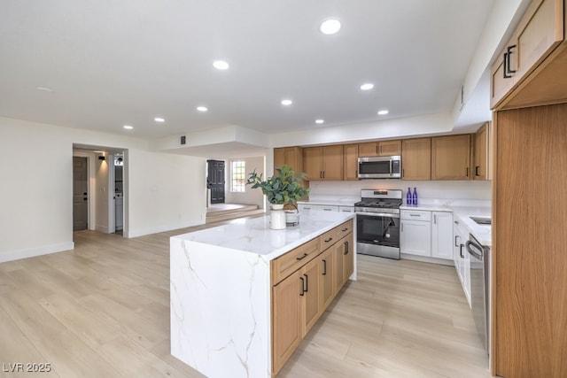 kitchen featuring light stone countertops, light wood finished floors, a kitchen island, recessed lighting, and stainless steel appliances