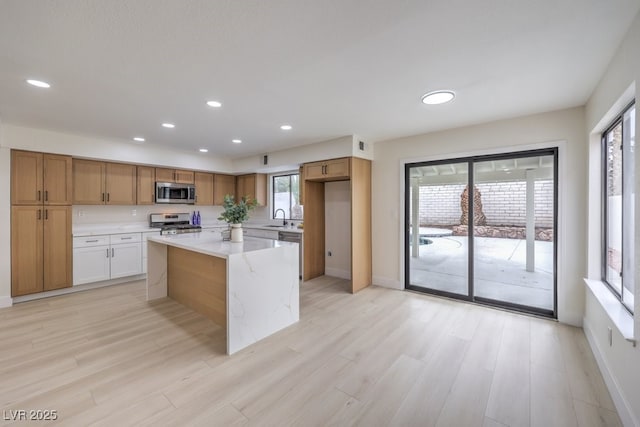 kitchen with light wood-style flooring, recessed lighting, stainless steel appliances, a kitchen island, and a sink