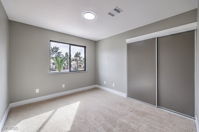 unfurnished bedroom with carpet floors, a closet, visible vents, and baseboards