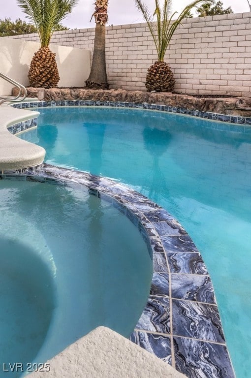 view of swimming pool featuring a pool with connected hot tub and a fenced backyard