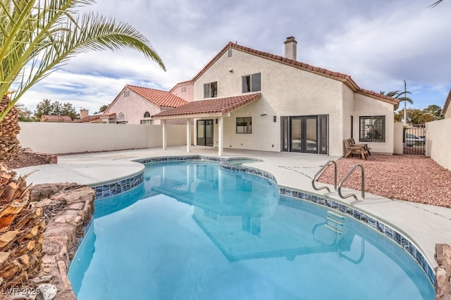 view of pool with a fenced backyard, a pool with connected hot tub, a patio, and french doors