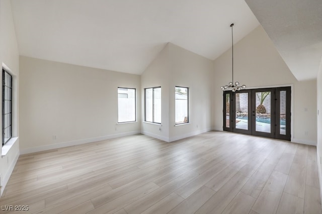 unfurnished living room featuring french doors, baseboards, and light wood finished floors