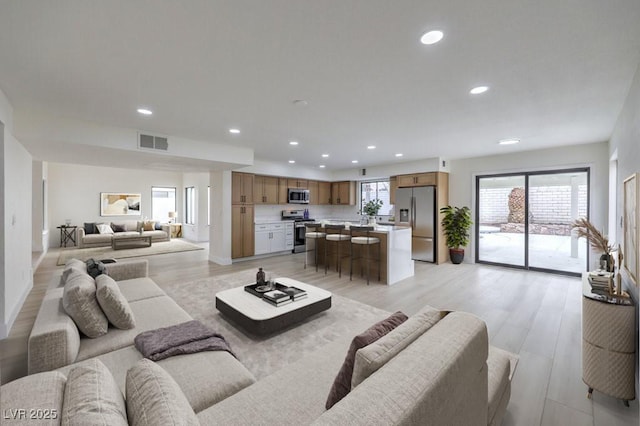 living area with light wood-style floors, visible vents, and recessed lighting