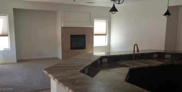 kitchen with a fireplace, a sink, hanging light fixtures, and carpet flooring