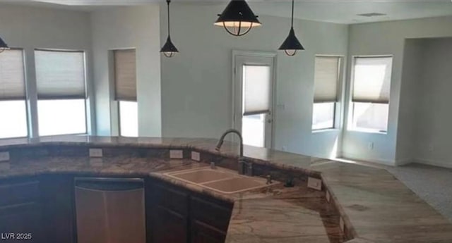 kitchen with plenty of natural light, decorative light fixtures, a sink, and stainless steel dishwasher