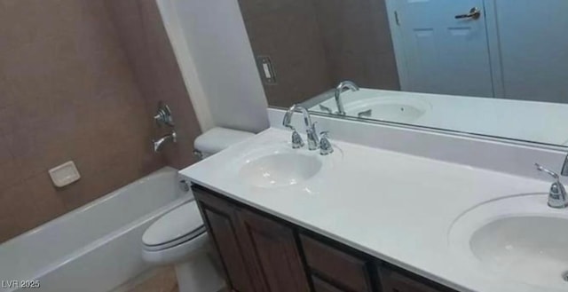 full bath featuring double vanity, a sink, and toilet