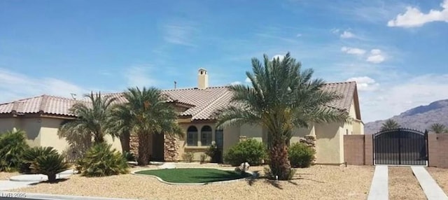 view of front of house with a gate, a tile roof, and stucco siding