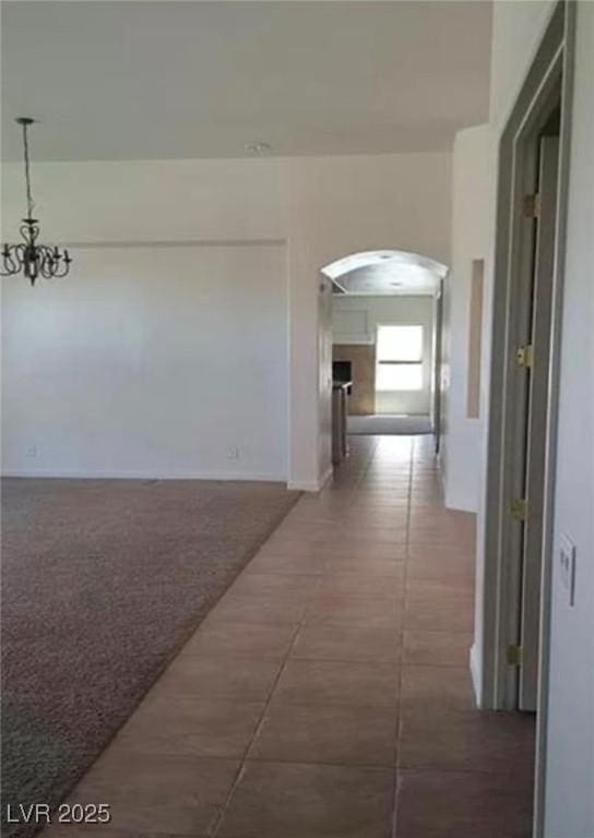 hall featuring arched walkways and an inviting chandelier