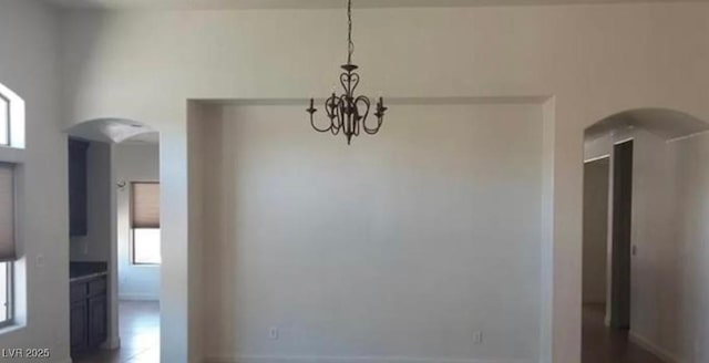 unfurnished dining area with a chandelier and arched walkways