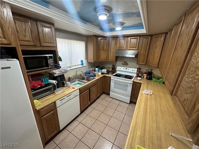 kitchen featuring a tray ceiling, light countertops, a sink, white appliances, and under cabinet range hood