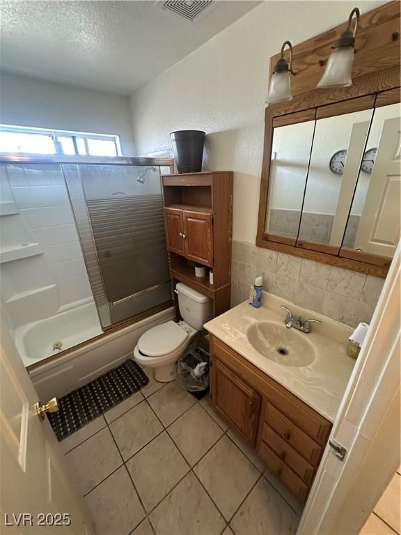 bathroom with toilet, vanity, tile walls, and tile patterned floors