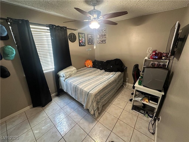 bedroom featuring a ceiling fan, light tile patterned flooring, a textured ceiling, and baseboards