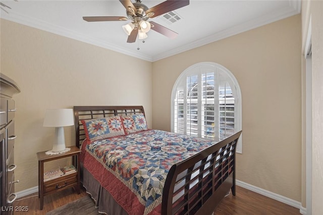 bedroom featuring visible vents, baseboards, wood finished floors, and ornamental molding