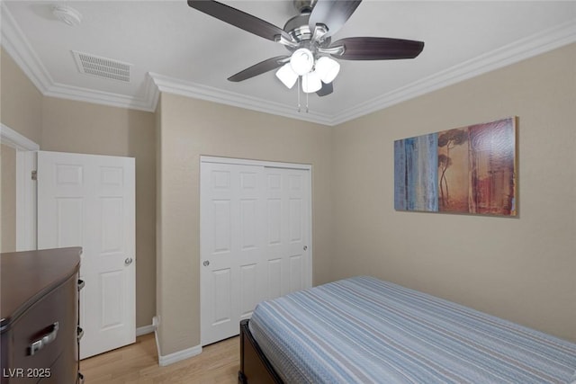 bedroom with visible vents, ceiling fan, a closet, crown molding, and light wood-type flooring