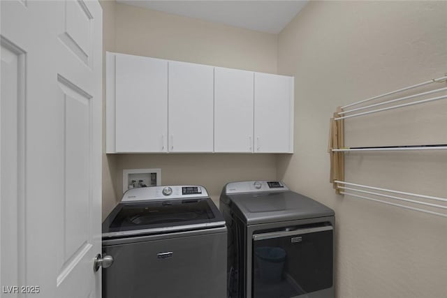 clothes washing area featuring separate washer and dryer and cabinet space