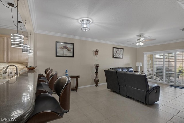 living room featuring crown molding, a ceiling fan, baseboards, and visible vents