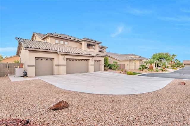 mediterranean / spanish house with concrete driveway, a tile roof, fence, central air condition unit, and stucco siding