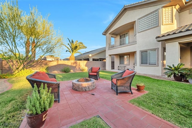 view of patio with an outdoor fire pit, a fenced backyard, and a balcony