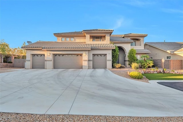 mediterranean / spanish-style home featuring a tile roof, fence, concrete driveway, and stucco siding