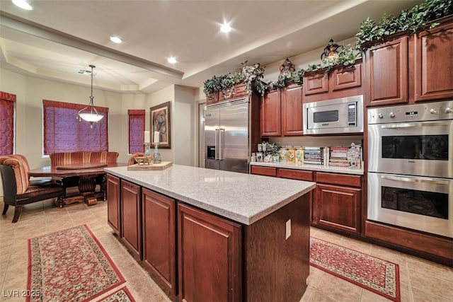 kitchen featuring built in appliances, recessed lighting, a kitchen island, a tray ceiling, and pendant lighting