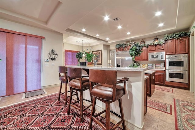 kitchen featuring built in appliances, light countertops, a tray ceiling, and visible vents