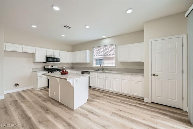 kitchen featuring recessed lighting, a sink, white cabinetry, appliances with stainless steel finishes, and a center island