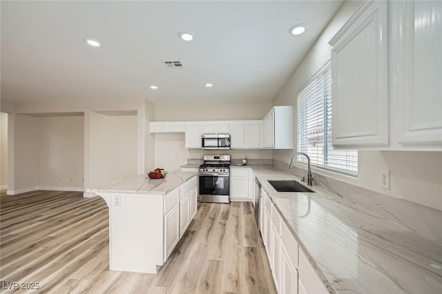 kitchen with light stone counters, visible vents, appliances with stainless steel finishes, a sink, and light wood-type flooring