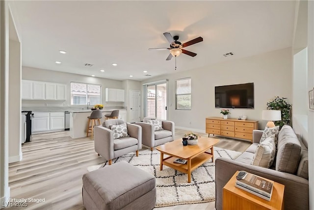 living area featuring light wood-style flooring, visible vents, and a wealth of natural light