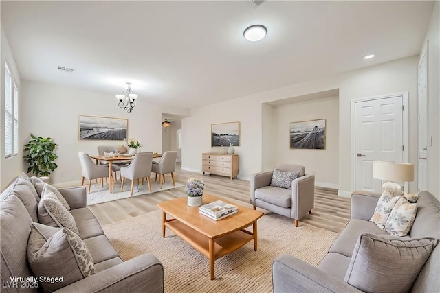 living room featuring recessed lighting, a notable chandelier, visible vents, baseboards, and light wood finished floors